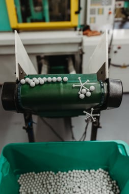 A machine dropping small white pieces into a bucket