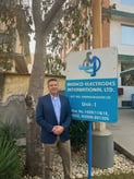 A picture of Micron's CEO, Bill Laursen, standing in front of a sign that says "Medico Electrodes International LTD'