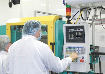 Two employees look at a injection molding machine screen