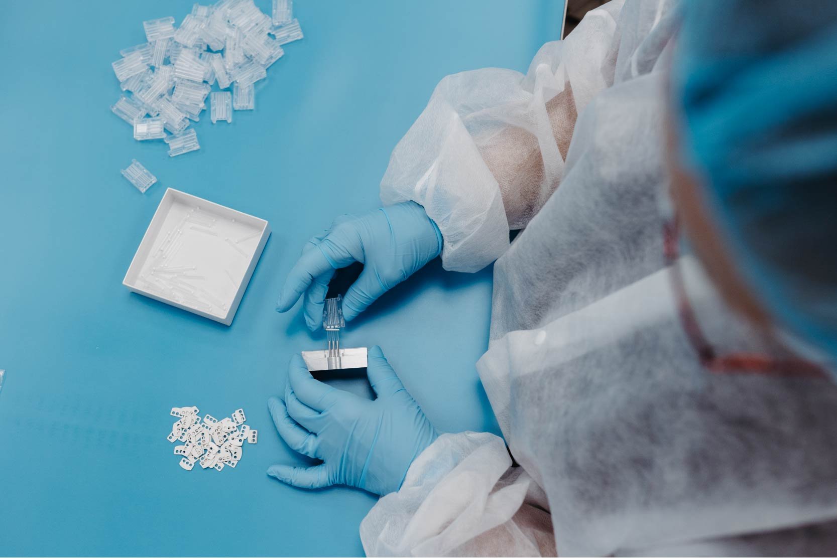 Woman wearing gloves carefully assembles a medical device