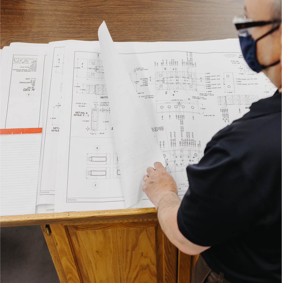 A man looks at pages of manufacturing blueprints