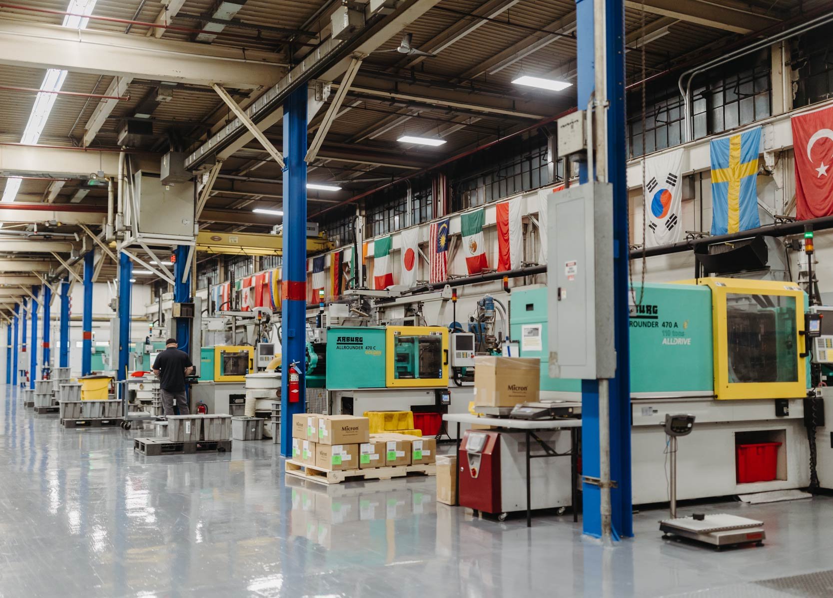 Four Arburg injection molding machines surrounded by flags of different countries